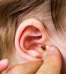 Close up photograph of a Parent touching a child's outer ear with their fingers