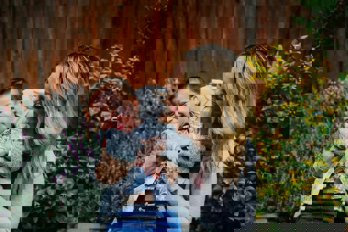 Parent or carer tickling a young child who is sitting on their lap, both smiling.